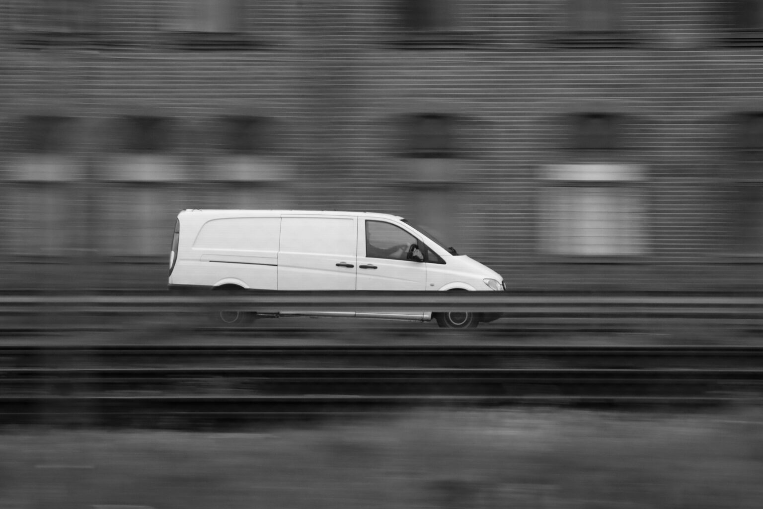 White van captured in motion blur against a city building in Jönköping, Sweden.